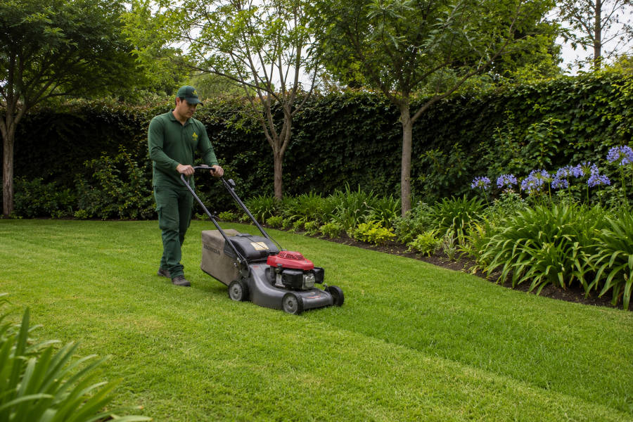 jardineiro a cortar a relva nun jardim em Portimao