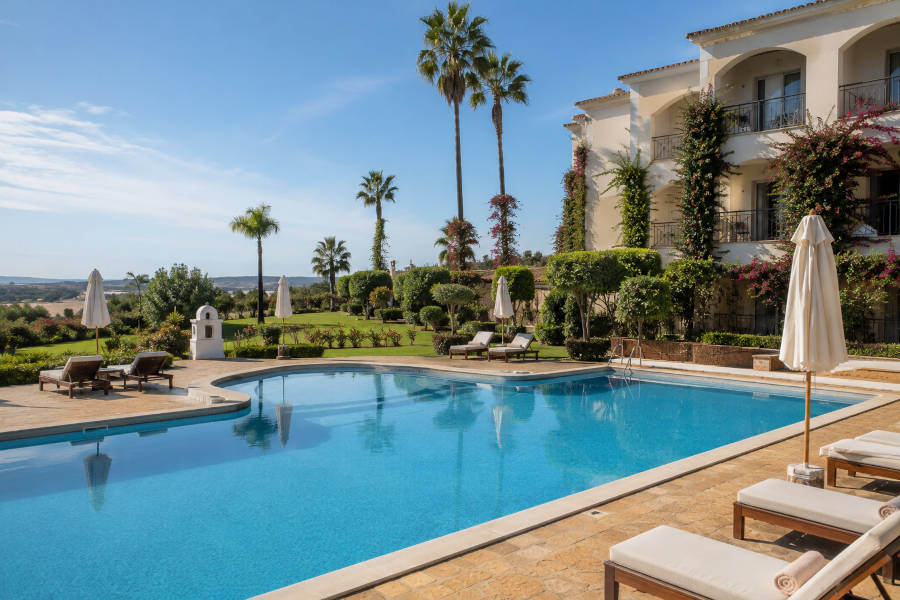 Piscina com espreguiçadeiras no jardim de um hotel