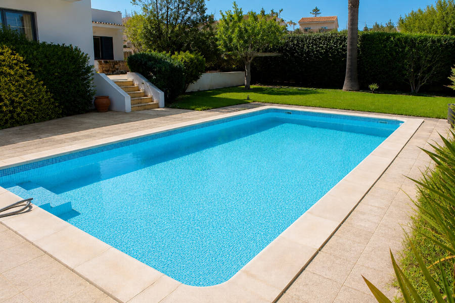 uma piscina limpa, com água límpida, no jardim de uma casa em Alvor