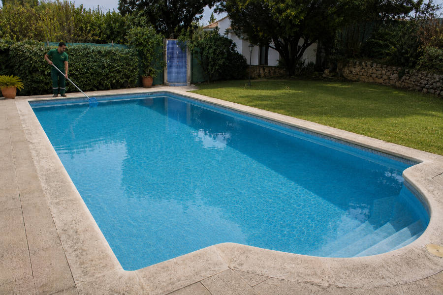 Piscina com água cristalina e borda de pedra branca