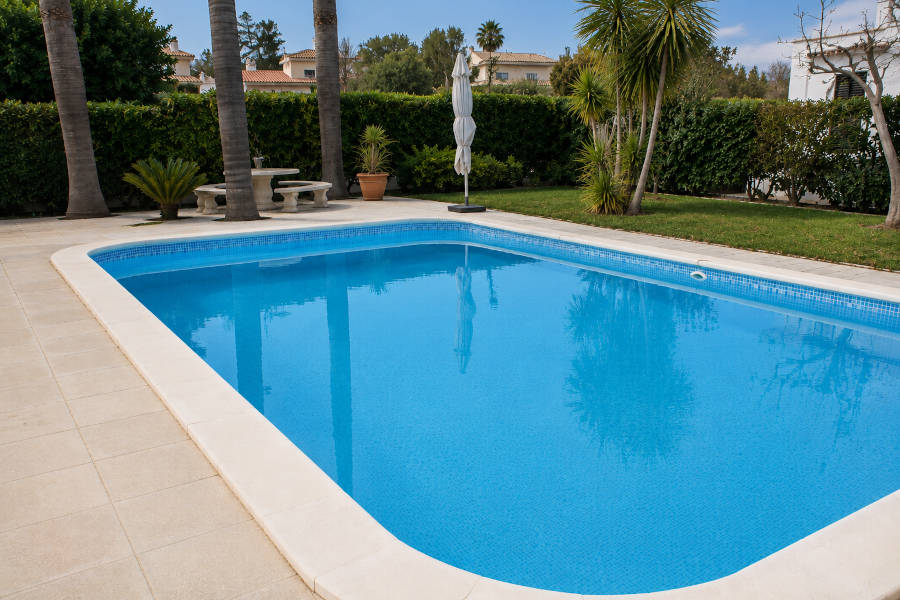 Piscina num condomínio, limpa e com um guarda-sol