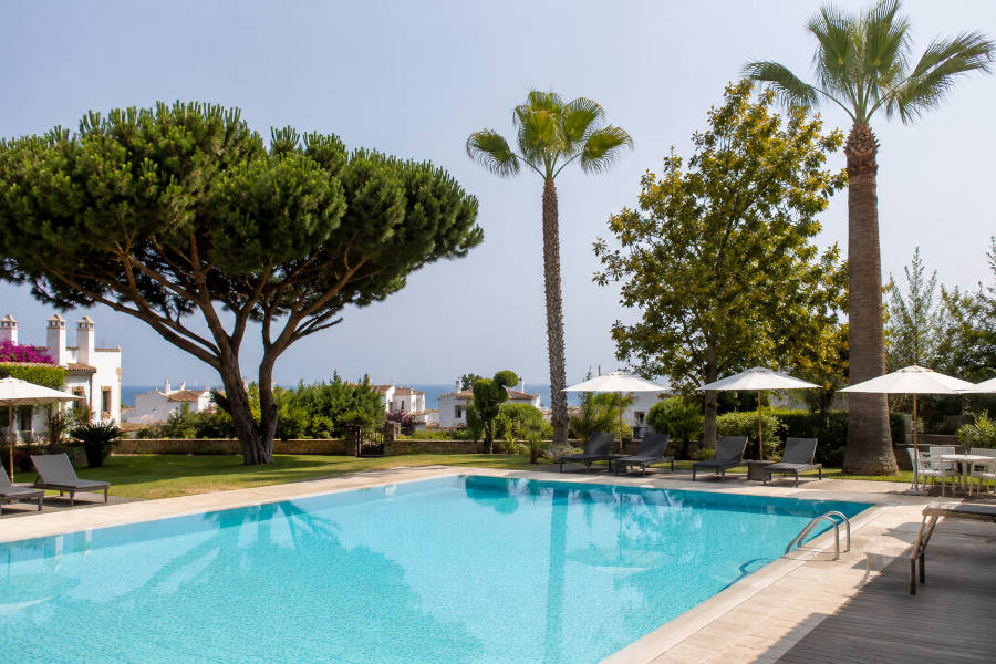 piscina com guarda-sóis e palmeiras no jardim de um hotel no Algarve